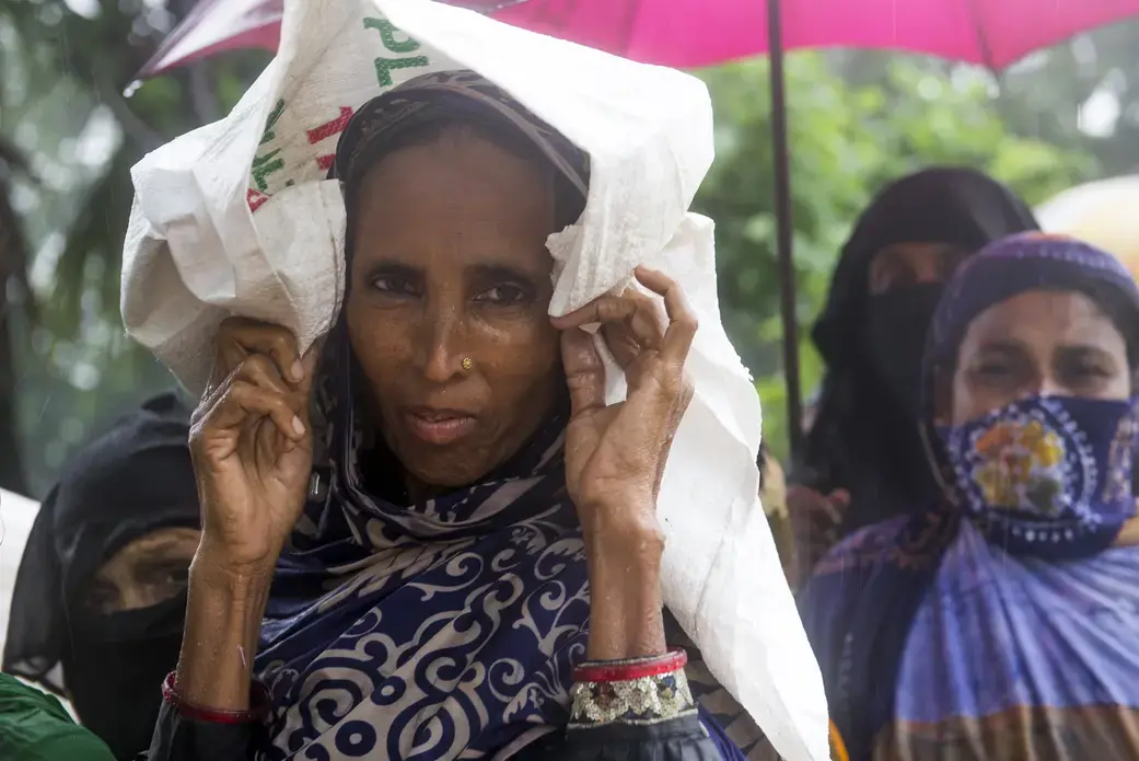 Khulna District -- Women wait in line in the rain to collect 20kgs of rice being given out by the government as part of a VGF (Vulnerable Group Feeding) program ahead of Eid-ul-fitr in a southwestern village of the country. Image by Nikita Sampath. Bangladesh, 2016. Media file: dsc_1397.jpg