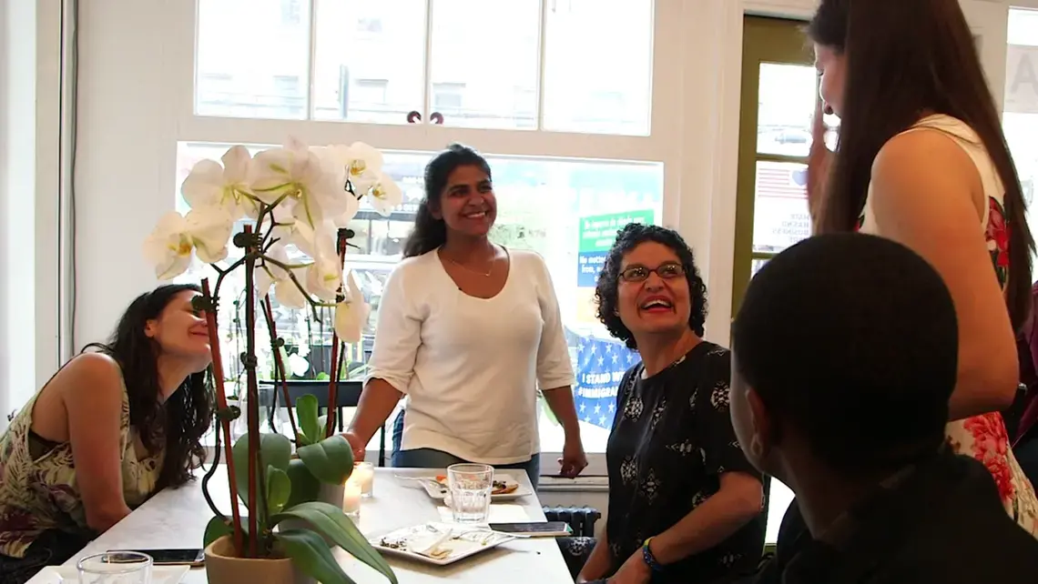 Adwa, a refugee, Kerry, founder of the Brooklyn cafe, and others celebrate at the Emma's Torch graduation ceremony. Image by Thea Piltzecker. New York City, 2018.