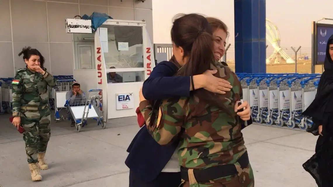 Lieutenant Kochar Saleh Haji, outside the Erbil International Airport, embraces a fighter from her peshmerga unit. Image by Kenneth Rosen. Iraq, 2017.
