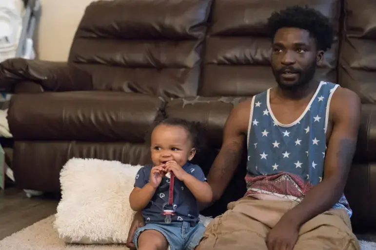 Theron Carson sits on the floor with his daughter watching cartoons. Carson was charged with trafficking marijuana and had $1,200 seized from his home after the police smelled weed coming from his Newburg apartment and conducted a search. Image by J. Tyler Franklin. United States, 2019. Theron Carson sits on the floor with his daughter watching cartoons. Carson was charged with trafficking marijuana and had $1,200 seized from his home after the police smelled weed coming from his Newburg apartment and conducted a search. Image by J. Tyler Franklin. United States, 2019.