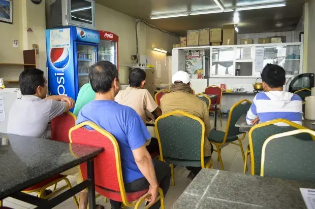 Nepalese migrant workers sit in a Nepalese restaurant near a labor camp north of Doha, Qatar. Image by Yam Kumari Kandel. Qatar, 2016. Media file: gpjnews_nepal_ykk_manpower_1_web-620x412.jpg
