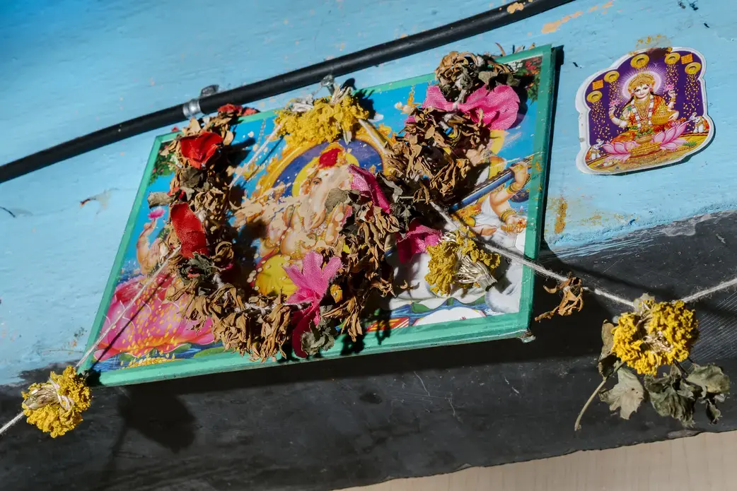 Garlands and images of deities hang over the doorway of an apartment in the Dharavi area of Mumbai. This particular part of Dharavi is home to many hijras, a formally recognized third gender in India. Image by Jake Naughton and Aarti Singh. India, 2018.