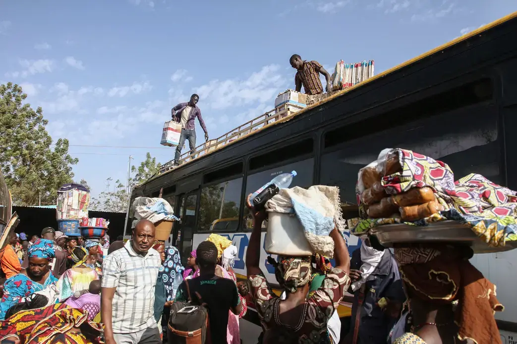 Buses idle at the main bus station in Bamako, Mali. Thousands of migrants each year board buses like these bound for Gao, from where they will cross the Sahara to Algeria. Image by Anthony Fouchard. Mali, 2017.