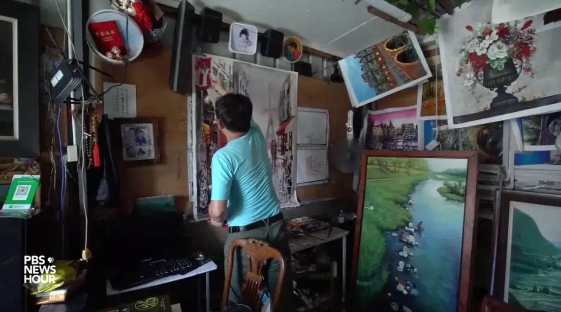 Artist Zeng Muquan has never set foot outside China, but he's painted tens of thousands of European scenes from his studio in the country's southern Guangdong province. Image by PBS NewsHour. China, 2019. Artist Zeng Muquan has never set foot outside China, but he's painted tens of thousands of European scenes from his studio in the country's southern Guangdong province. Image by PBS NewsHour. China, 2019.