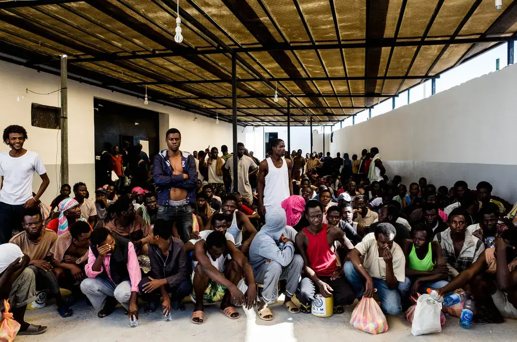 Migrants, mostly from West Africa, wait to receive daily food rations at the Triq al-Sikka detention center in Tripoli, Libya. Image by Peter Tinti. Libya, 2017. Migrants, mostly from West Africa, wait to receive daily food rations at the Triq al-Sikka detention center in Tripoli, Libya. Image by Peter Tinti. Libya, 2017.