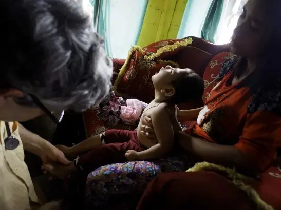 Doctors examine 2-year-old Rifki Aldiansyah for symptoms of mercury poisoning. Rifki was in good health until his third month when he began losing motor control. Rifki's mother, right, lived in Cisungsang, a nearby mining community, and said her home was surrounded by gold processing centers. Image by Larry C. Price. Indonesia, 2015. Media file: 2015_price_olympus_mercury_050.jpg