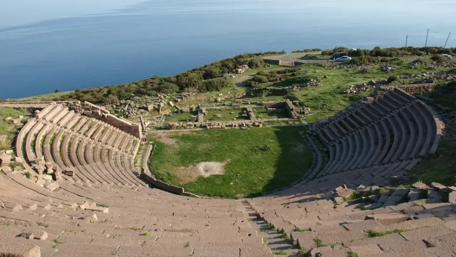 The ancient Theatre of Assos overlooking the Aegean Sea, with the nearby island of Lesbos on the horizon. Image courtesy of Vindobona/Wikimedia Commons. Media file: assos_theatre.jpg