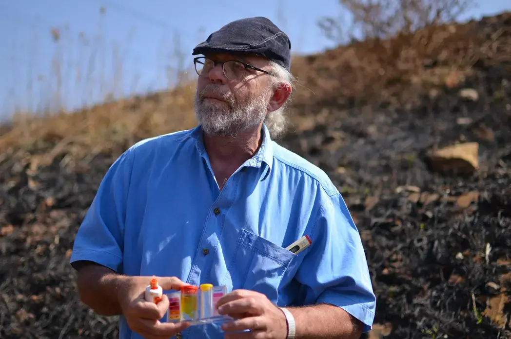 David van Wyk tests water quality in streams near piles of mine waste in Riverlea. Image by Mark Olalde. South Africa, 2016. David van Wyk tests water quality in streams near piles of mine waste in Riverlea. Image by Mark Olalde. South Africa, 2016.