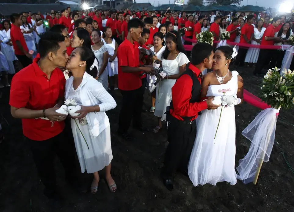 Newly wed couples kiss during a February mass wedding ceremony at Rosario town in Cavite City, south of Manila. Image by Romeo Ranoco. Philippines, 2014. Media file: screen_shot_2014-10-14_at_11.59.09_am.png