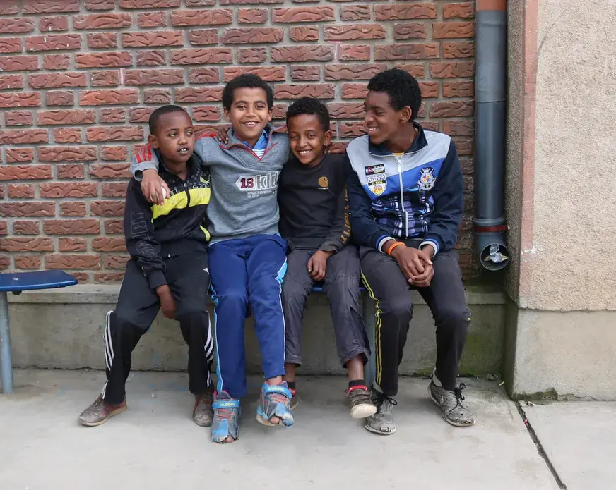 Four boys pose for a photo at Kidana Mehert Children’s Home in Addis Ababa. These boys were playing soccer together with a small ball they found. They live in the home and will continue to live there until they are 18. After they finish school they will decide to work or go to college. This children’s home allows local adoption so anyone of the kids who currently living there can be adopted. Image by Abigail Bekele. Ethiopia, 2018. Four boys pose for a photo at Kidana Mehert Children’s Home in Addis Ababa. These boys were playing soccer together with a small ball they found. They live in the home and will continue to live there until they are 18. After they finish school they will decide to work or go to college. This children’s home allows local adoption so anyone of the kids who currently living there can be adopted. Image by Abigail Bekele. Ethiopia, 2018.