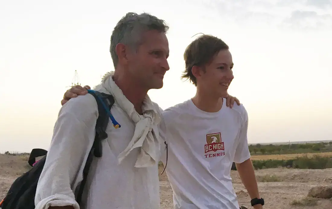 At the end of the second day of hiking, Paul Salopek and Boy Scout Nicholas Fahy pose together in the Kyzyl Kum Desert. Image by Mark Schulte. Uzbekistan, 2016. Boy Scout Nicholas Fahy with Paul Salopek on the Out of Eden Walk.