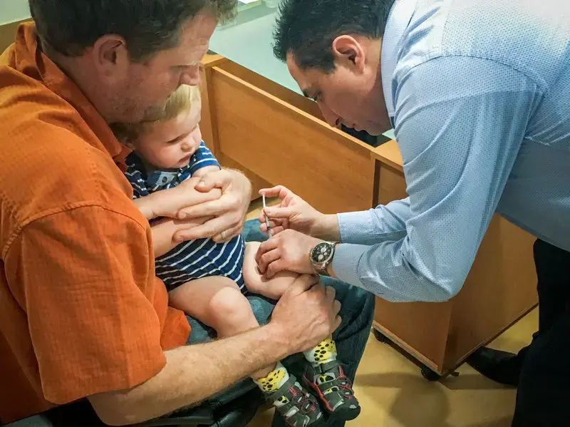 Erik Vance holds his son while a pediatrician administers vaccinations. Image courtesy Erik Vance. Mexico, 2017.