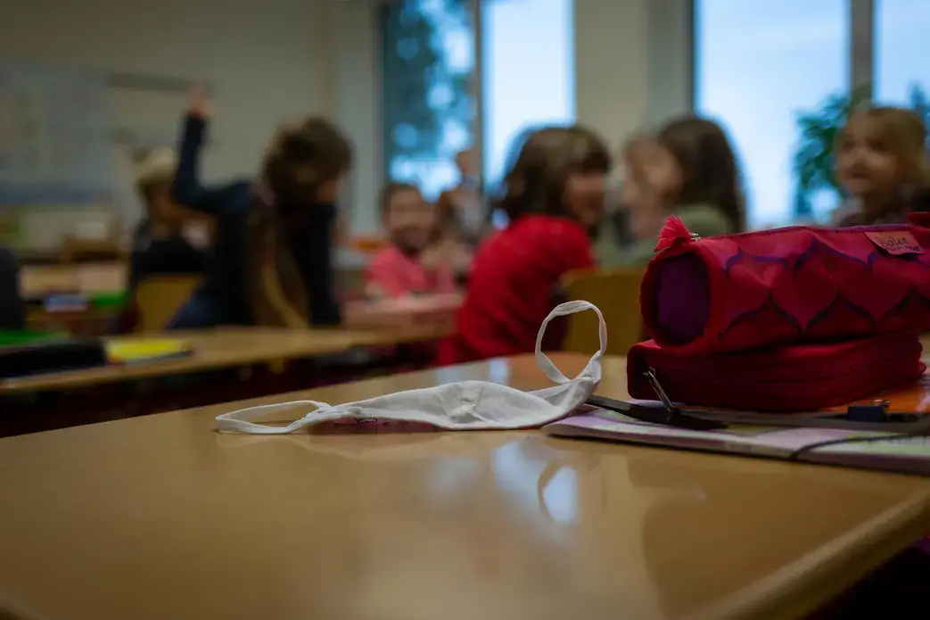 A mask sits on a desk at a primary school in Weimar, Germany. Students are required to wear masks in the hallways and on the playground but not while sitting in class. If coronavirus cases increase in the community or are found in the school, then tighter restrictions are implemented. Image by Ryan Delaney / St. Louis Public Radio. Germany, 2020. A mask sits on a desk at a primary school in Weimar, Germany. Students are required to wear masks in the hallways and on the playground but not while sitting in class. If coronavirus cases increase in the community or are found in the school, then tighter restrictions are implemented. Image by Ryan Delaney / St. Louis Public Radio. Germany, 2020.