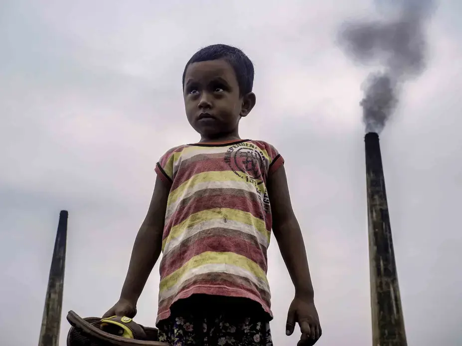 Four-year-old Nayem often plays atop large piles of coal used to fire kilns at a brick factory at the edge of Dhaka, Bangladesh. The chimneys from such factories contribute to some of the worst air pollution in the world. Image by Larry C. Price. Bangladesh, 2018. Four-year-old Nayem often plays atop large piles of coal used to fire kilns at a brick factory at the edge of Dhaka, Bangladesh. The chimneys from such factories contribute to some of the worst air pollution in the world. Image by Larry C. Price. Bangladesh, 2018.