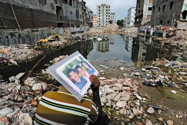An open wound: In front of the Rana Plaza site, Abdur Rahman holds a photo of his wife, Cahyna Akhter, who was killed there. Image by Andrew Biraj/Reuters. Bangladesh, 2013. Media file: rana_plaza_ruins_rtr_img.jpg