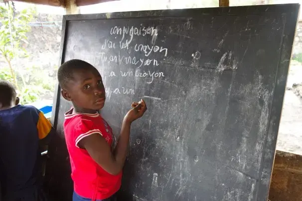Marceline Bauma, 8, lives in Goma, Congo. Some of Marceline’s life in that African city is far different than life in the United States. Her home has no electricity or running water. But other parts are familiar: There’s schoolwork to do, and her help is needed around the house. Image by Kem Knapp Sawyer. Congo, 2013. Media file: marcelineboard.jpg