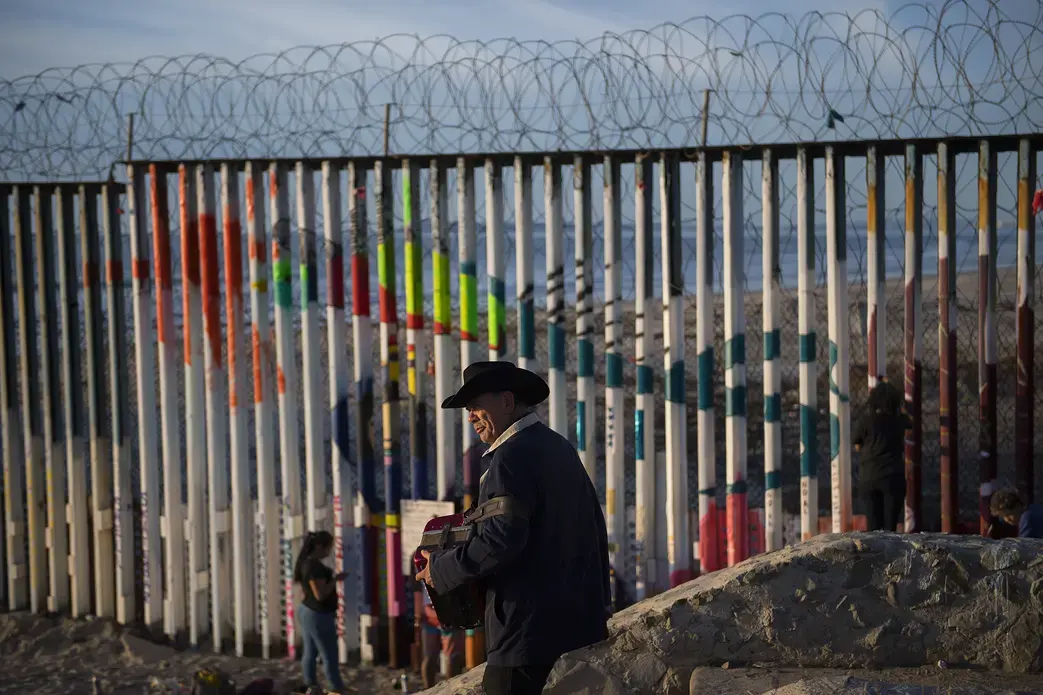 A musician visits the border wall at Playas de Tijuana at sunset Dec. 1. The artwork on the border wall is temporary and changes frequently. Image by Amanda Cowan. Mexico, 2019.