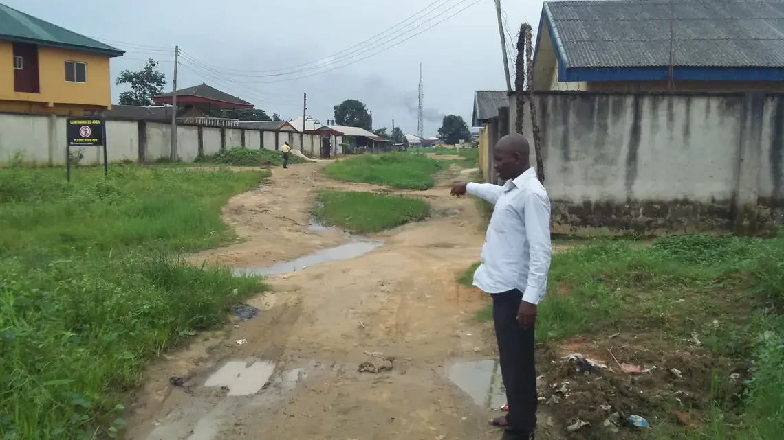 Sebastian Kpalap in Oghale village. The whole area is contaminated due to repeated oil spills. Kpalap points to a spot near his house where soldiers with guns harassed him while a technical crew inspected an oil spill on his land. "Some members of this Oghale community were shot dead for merely passing on this pipeline to their farm land," he said. Image by Ameto Akpe. Nigeria, 2012. Media file: 100_1159.JPG