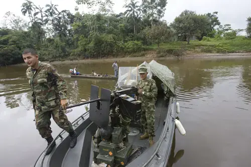 A navy officer walks over an armored Piraña boat used to fight guerrillas along the Tapaje river, Pueblo Nuevo, Colombia, July 8, 2007. Pueblo Nuevo, also known as Pulviza, was the scene of crude battles between the Colombian army and FARC guerrillas last April, leaving the town without a single resident. 1