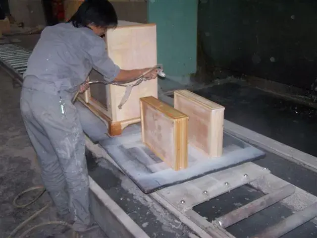 This photo was taken in a factory in China that exports furniture to the U.S. The workers do not always use masks while painting, and do not use ventilated spray booths for painting, as required under U.S. OSHA regulations. The dust and paint particles are still in the air. Paint contains carcinogenic tuolene and/or benzene and have caused leukemia in Chinese factory workers making products for the U.S. Image by Loretta Tofani. China, 2007. Media file: 1086.jpg