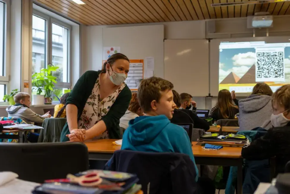 Teacher Inga Deppa works with students in an English class at Jacobishule in Kalletal, Germany. Masks were optional for students when they were seated at their desks, but the regional health authority has since tightened mask rules for older students. Image by Ryan Delaney/St. Louis Public Radio. Germany, 2020. Teacher Inga Deppa works with students in an English class at Jacobishule in Kalletal, Germany. Masks were optional for students when they were seated at their desks, but the regional health authority has since tightened mask rules for older students. Image by Ryan Delaney/St. Louis Public Radio. Germany, 2020.