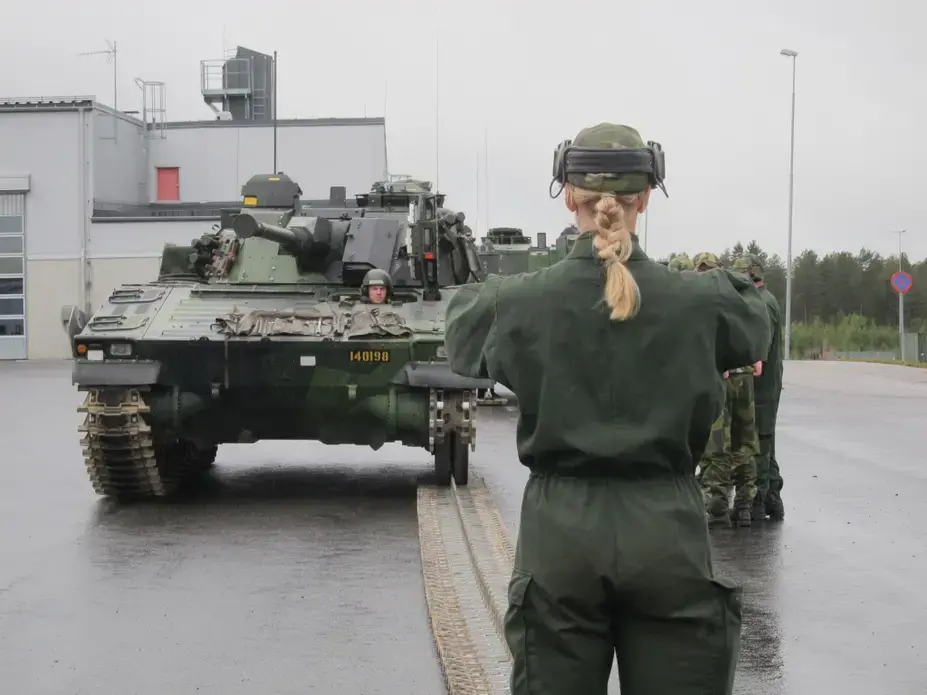 A female mechanized infantry conscript directs colleagues while learning to repair a CV90 combat vehicle. Image by Teresa Fazio. Sweden, 2018. A female mechanized infantry conscript directs colleagues while learning to repair a CV90 combat vehicle. Image by Teresa Fazio. Sweden, 2018.