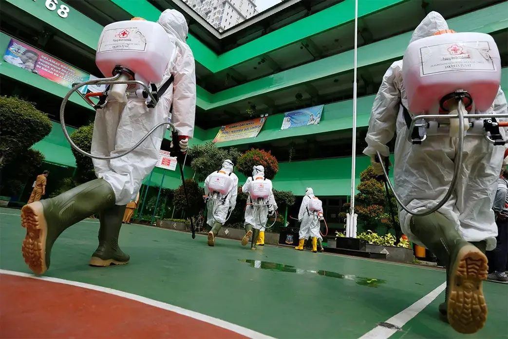 Volunteers from Indonesia's Red Cross prepare to spray disinfectant at a school closed amid the spread of coronavirus (COVID-19) in Jakarta. Image by REUTERS/Willy Kurniawan. Indonesia, 2020. Media file: coronavirus-reuters-small.jpg
