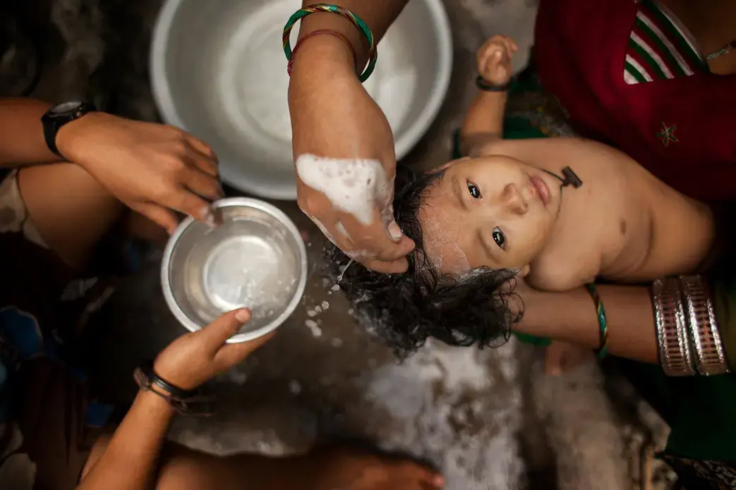 Deepika Shrestha is bathed in the streets by her mother in the village of Barah Chhetra. This image is part of Nepal: Water Rights on the Koshi River," a project produced by 2013 student fellows from SIU Carbondale. Image by Steve Matzker. Nepal, 2013. Media file: 1476391349865.jpg