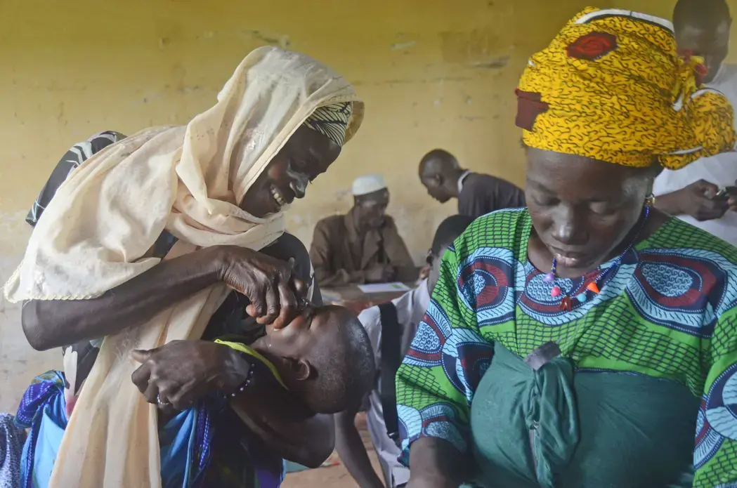 A mother gives her child malaria medicine to prevent the disease. Image by Amy Maxmen. Mali, 2013. Media file: _dsc2686.jpg