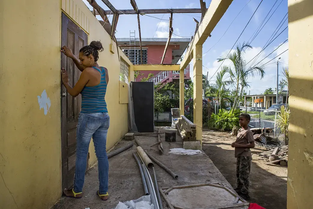 Rosalda Olma, a wife and mother to three kids, opens the front door to what remains of her home in Loiza. The entire home and contents were destroyed by the hurricane, and the family is living in a nearby school for the time being. “It’s hard getting used to these living conditions,” she said. “All five of us are trying to fit inside a single room.” Image by Ryan Michalesko. Puerto Rico, 2017. Rosalda Olma, a wife and mother to three kids, opens the front door to what remains of her home in Loiza. The entire home and contents were destroyed by the hurricane, and the family is living in a nearby school for the time being. “It’s hard getting used to these living conditions,” she said. “All five of us are trying to fit inside a single room.” Image by Ryan Michalesko. Puerto Rico, 2017.