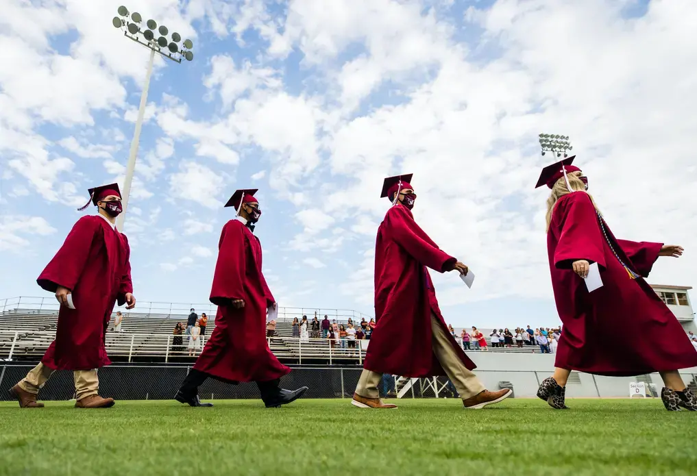 In Sherman, Texas, high school students wearing masks participate in a socially-distanced commencement ceremony. Image by Sara Carpenter / Shutterstock. United States, 2020.