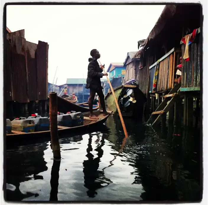 From the Everyday African Instagram feed (@everydayafrica): "A man visits from his boat in Iwaya—a neighborhood partially on stilts in the black waters of the Lagos Lagoon—in Lagos, Nigeria, August 16, 2013." Image by Allison Shelley. Nigeria, 2013.