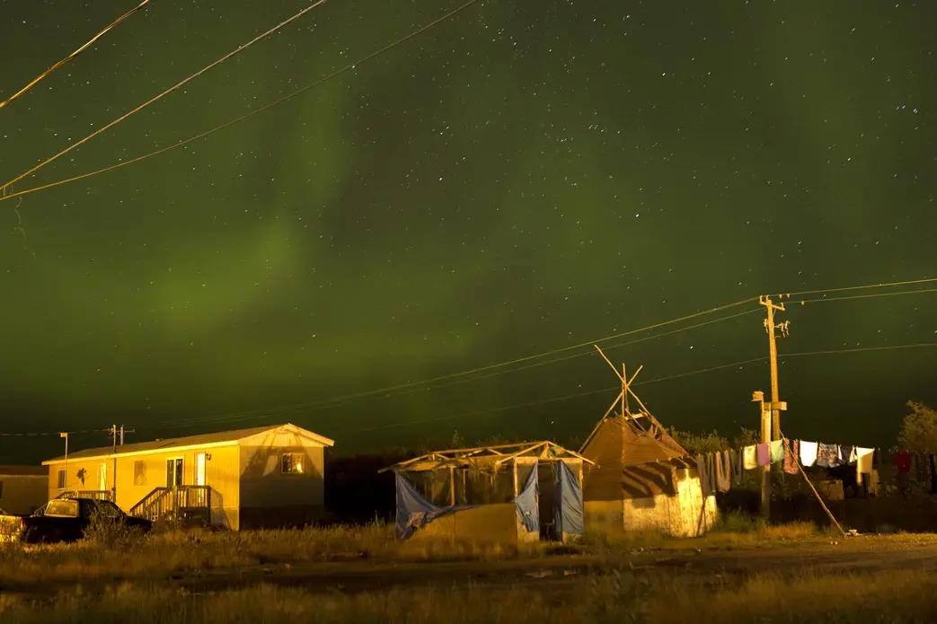 The northern lights fill the sky over the remote First Nations community of Attawapiskat. Attawapiskat is an isolated First Nation community located in northern Ontario, Canada, at the mouth of the Attawapiskat River on James Bay. On April 9, 2016, the community of approximately 2,000 people declared a state of emergency after being overwhelmed with attempted suicides, over 100 attempts in a 10-month period. Image by David Maurice Smith/Oculi. Canada, 2016. David Maurice Smith_Attawapiskat_Pulitzer Grant