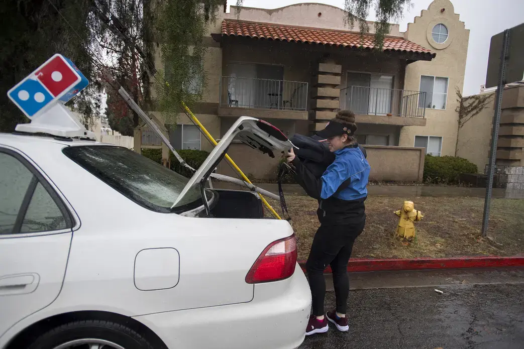 Leslie Flores transfers fresh pizzas into her car while on a delivery for Domino’s in Chula Vista, Calif., on Nov. 27. Leslie stays busy as a driver to help her family make ends meet, in addition to keeping up with her college classes. Image by Amanda Cowan. United States, 2019.