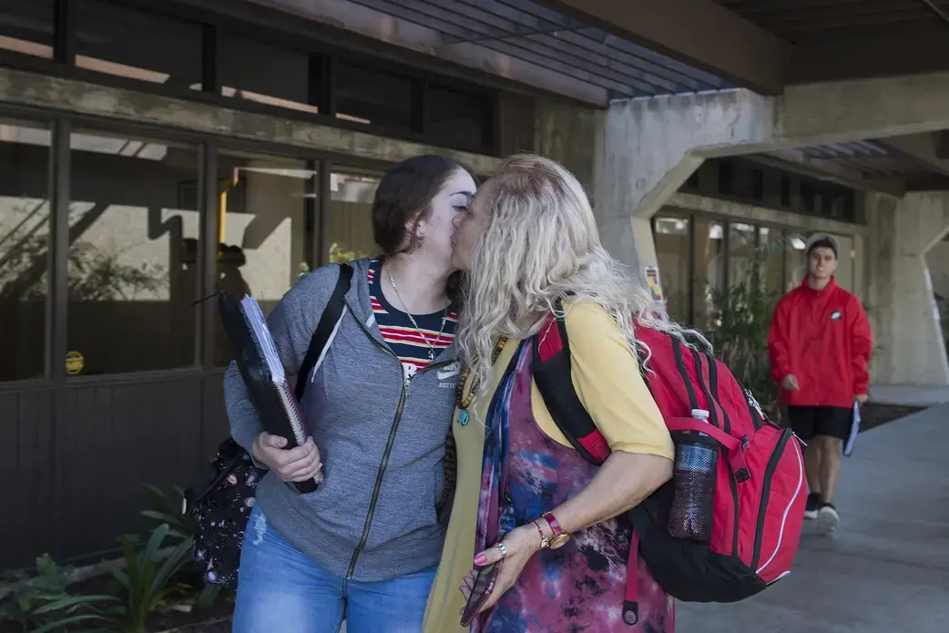 Leslie Flores, 23, shares a quick kiss with her mother, Enedis, 54, as they part ways between classes after running into each other on campus Nov. 26 at Southwestern College in Chula Vista, Calif. Image by Amanda Cowan. United States, 2019.