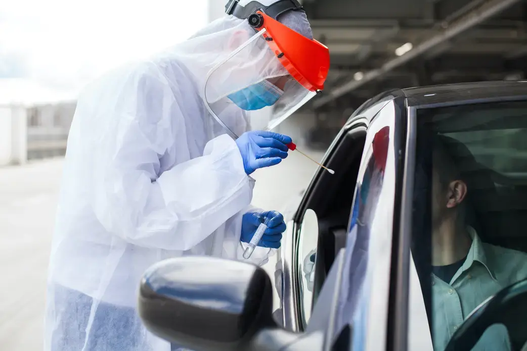 A medical worker administers a COVID-19 swab at a mobile testing center. In the fall of 2020, Novavax launched a phase III COVID-19 vaccine trial in the United Kingdom. Image by Cryptographer / Shutterstock. United Kingdom, 2020. A medical worker administers a COVID-19 swab at a mobile testing center. In the fall of 2020, Novavax launched a phase III COVID-19 vaccine trial in the United Kingdom. Image by Cryptographer / Shutterstock. United Kingdom, 2020.