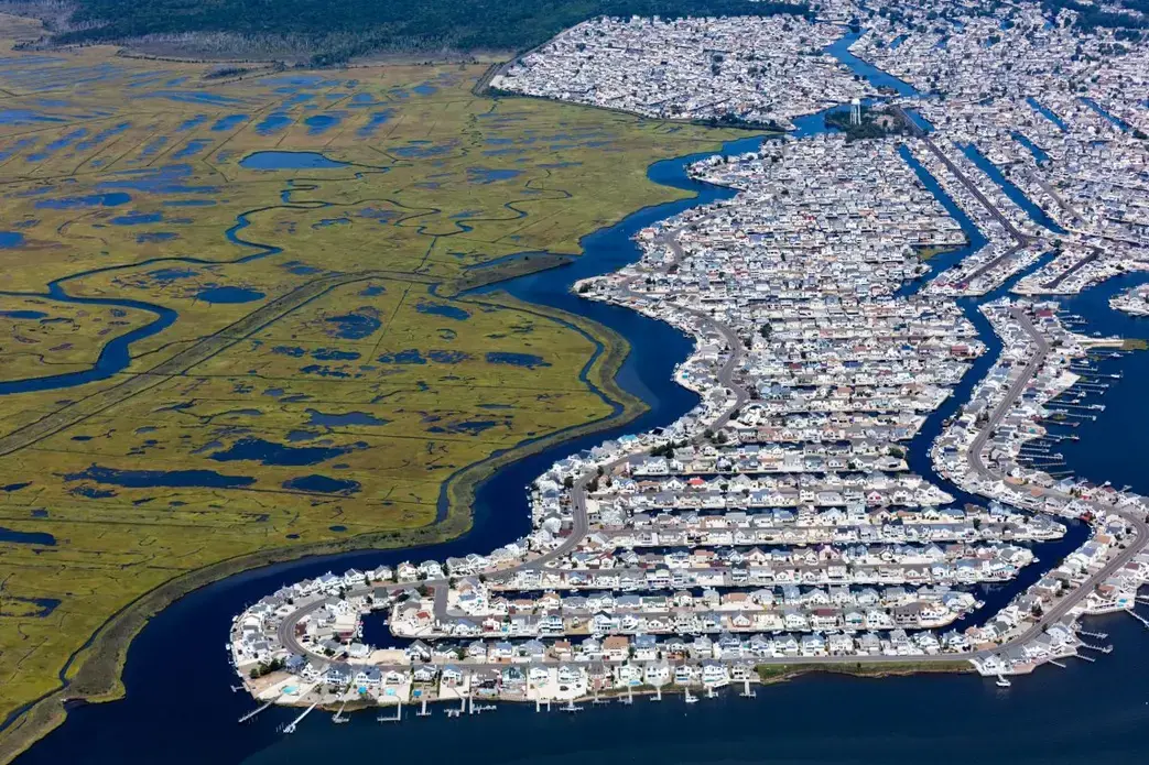 The subdivision Beach Haven West was carved out of a New Jersey salt marsh beginning in 1945. The passage of the state Wetlands Protection Act of 1970 prevented additional loss of wetlands in New Jersey. Scientists with Rutgers University in New Jersey forecast a rise of sea level along the state’s shoreline of as much as 106 centimeters by 2100. That would inundate a large percentage of this community of almost 4,000 people. Image by Alex MacLean. United States, 2019. The subdivision Beach Haven West was carved out of a New Jersey salt marsh beginning in 1945. The passage of the state Wetlands Protection Act of 1970 prevented additional loss of wetlands in New Jersey. Scientists with Rutgers University in New Jersey forecast a rise of sea level along the state’s shoreline of as much as 106 centimeters by 2100. That would inundate a large percentage of this community of almost 4,000 people. Image by Alex MacLean. United States, 2019.