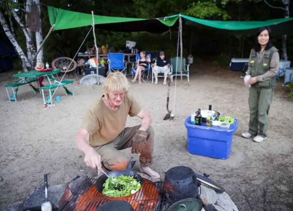 Duane Hanson cooks up vegetables grown at his homestead during the annual Hanson family camping trip at Spencer Lake in T3 R5, in the Unorganized Territories of Maine, on Aug. 3, 2019. Image by Michael G. Seamans. United States, 2019.