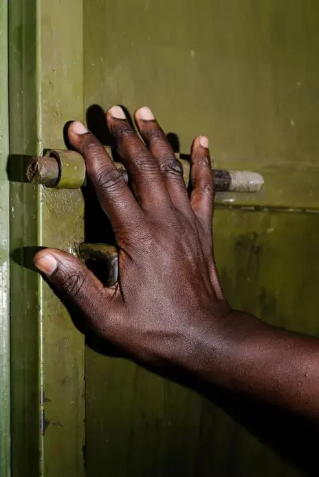 A priest, one of the old guard of LGBTQ rights advocacy in Uganda and Kenya, poses for a portrait at his home outside of Kampala. He had been defrocked due to his advocacy and has just become a priest again. He did not want to show his face in order to protect his livelihood. Image by Jake Naughton. Uganda, 2017.