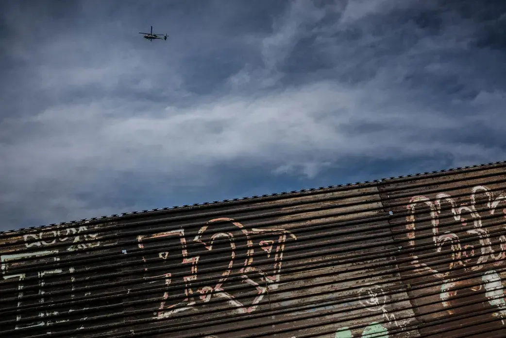 A U.S. Border Patrol helicopter watches over the border separating Tijuana, Mexico and San Diego, California. Image by James Whitlow Delano. Mexico, 2017.