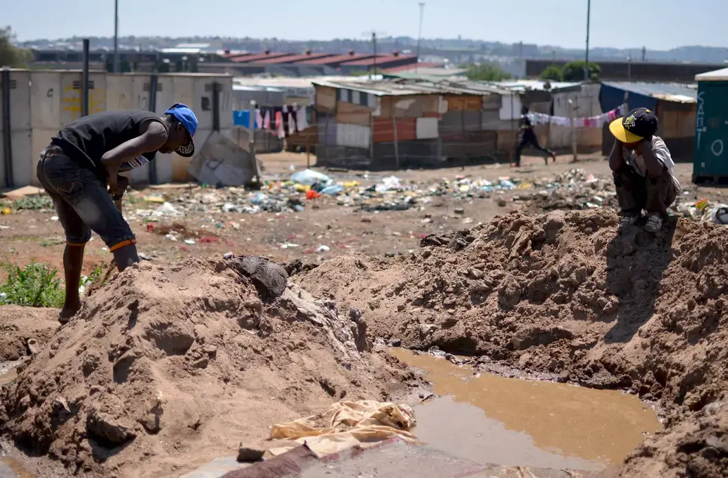 A child watches an illegal miner process gold ore by hand in a Johannesburg informal settlement. Image by Mark Olalde. South Africa, 2017.