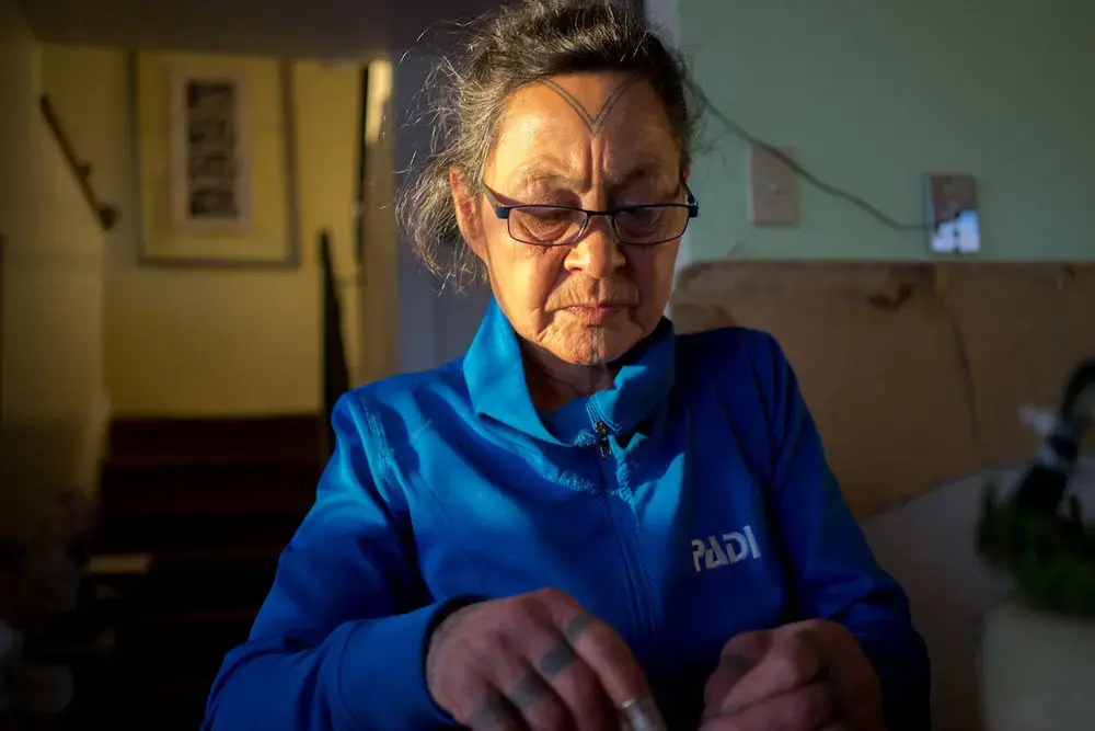 Aaju Peter sews a tie out of sealskin in her home. Image by Nick Mott. Canada, 2018.