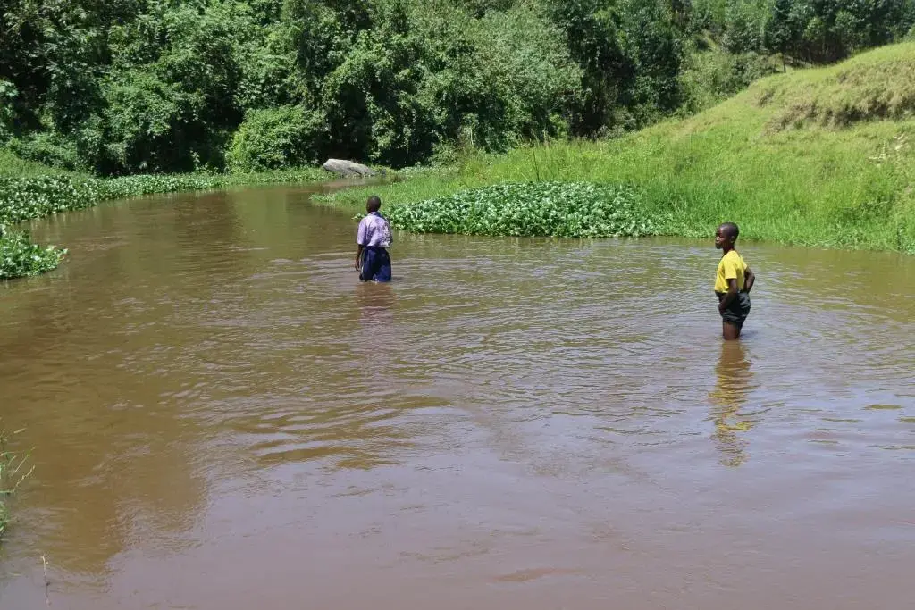 Two children standing in the Rwizi River