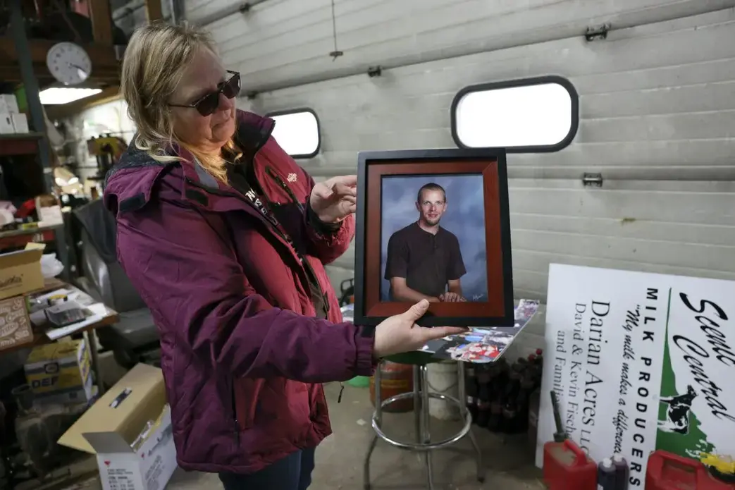 Amy Fischer and her son Brian. Amy Fischer is seen with a photo of her son, Brian, on her family’s 350-cow dairy farm, Darian Acres, in Rio, Wis., on Dec. 18, 2020. Brian died by suicide at the age of 33, on Dec. 21, 2016. The Fischers attribute his death to a combination of stress from work, a drinking problem and depression from a recent break-up. Dairy farmers and their advocates say numerous stressors are leading to a mental health crisis in their industry, including financial pressures, long hours, labor shortages and harsh weather.