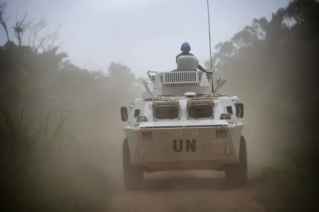 An armored UN personnel carrier on patrol drives down a road.