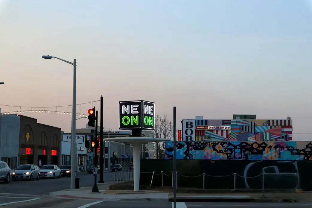A neon sign reading "NEON" is lit up against the dusk sky.