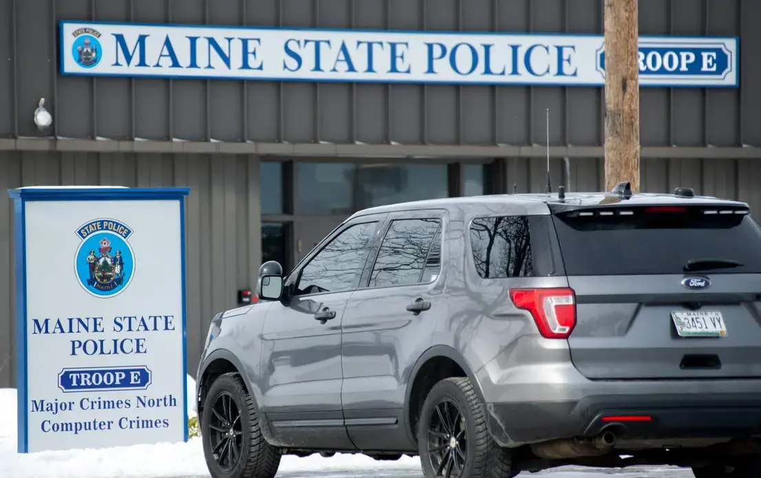 A gray SUV is parked in front of a Maine State Police building.