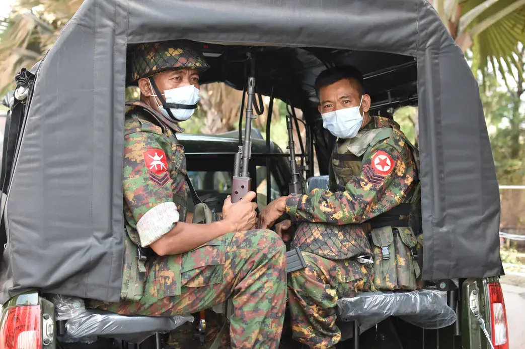 Soldiers in medical face masks sit in a truck.