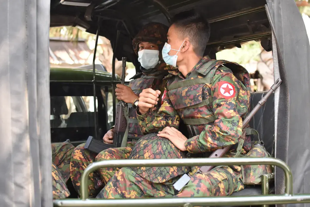 Soldiers wearing medical masks sit in a vehicle.