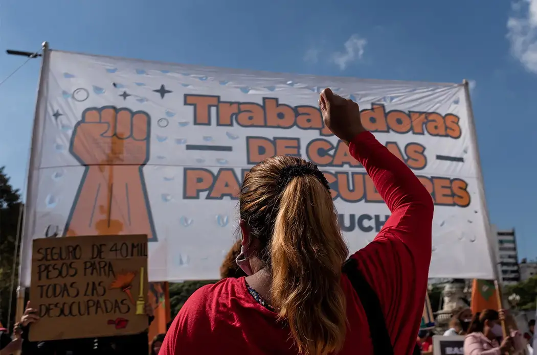 anita_pouchard_serra_nota.jpeg Someone, with their back to the camera, raises their fist during a protest.